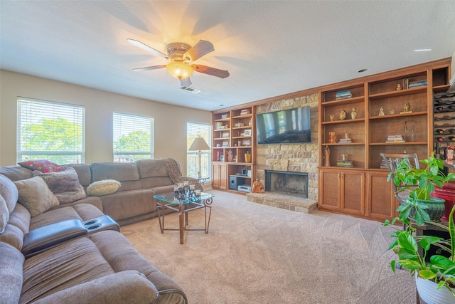 living area with a ceiling fan, a healthy amount of sunlight, a stone fireplace, and visible vents
