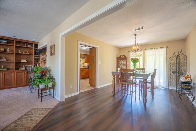 dining space with visible vents, a textured ceiling, a notable chandelier, and dark wood-style flooring