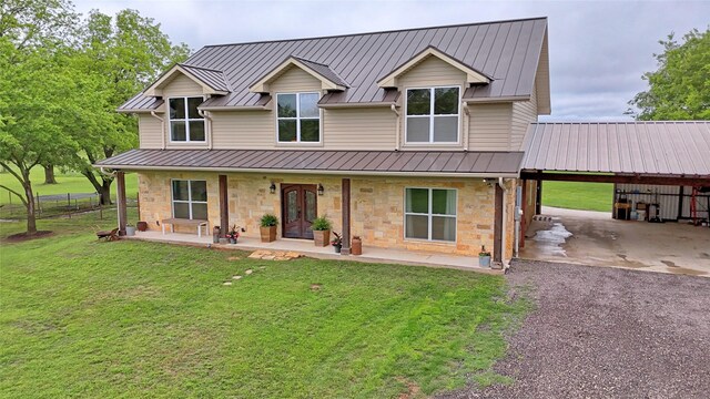back of property featuring a standing seam roof, a yard, metal roof, and stone siding