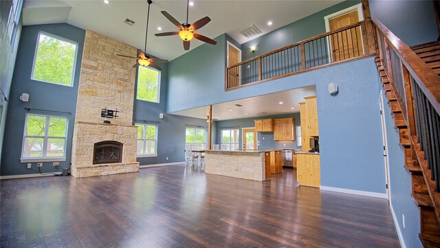 unfurnished living room featuring visible vents, a ceiling fan, stairs, and high vaulted ceiling