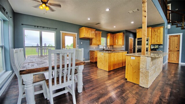 kitchen with a center island, stainless steel double oven, dark wood finished floors, and ceiling fan