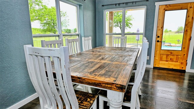 dining space with a textured wall, baseboards, and dark wood-type flooring