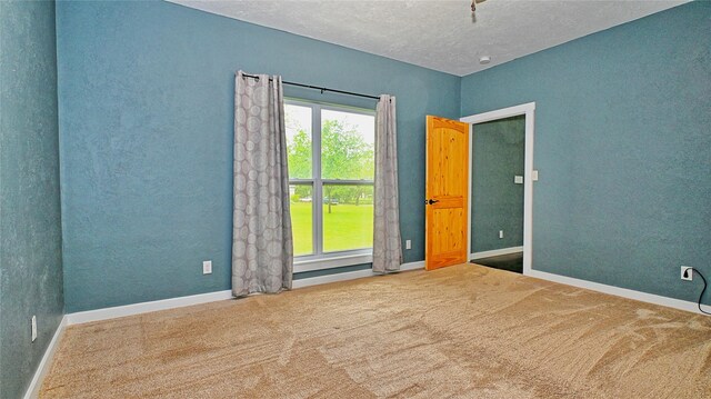 spare room with carpet floors, a textured ceiling, and baseboards