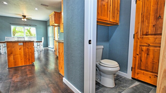 bathroom with a ceiling fan, a textured wall, and toilet
