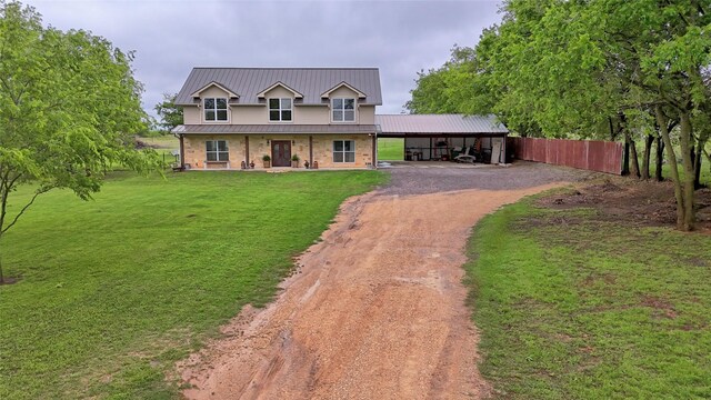 view of front of home with metal roof, a front yard, dirt driveway, fence, and an attached carport