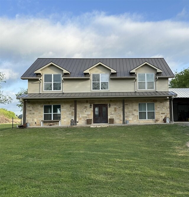 back of property featuring a standing seam roof, a yard, metal roof, and stone siding