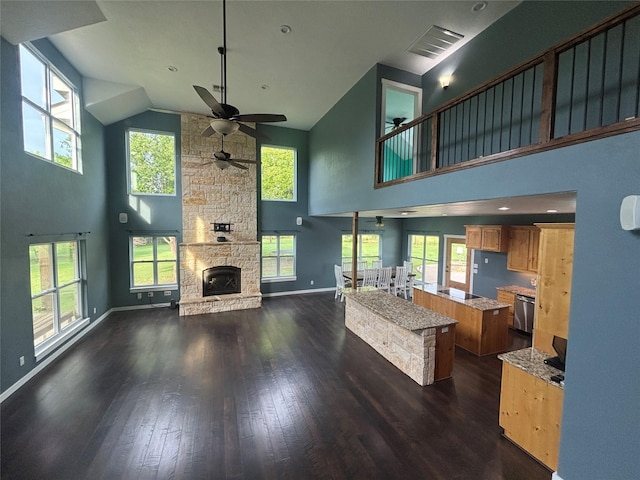 209 E Meadows St, Saint Jo, TX 76265 - living room featuring high vaulted ceiling, a ceiling fan, dark wood-style floors, a stone fireplace, and plenty of natural light