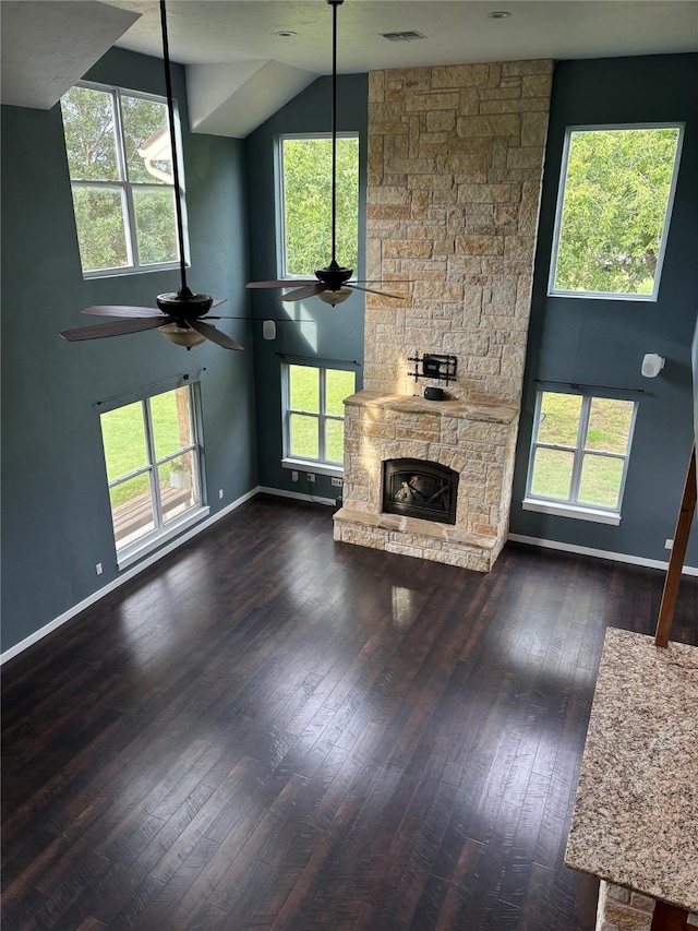 209 E Meadows St, Saint Jo, TX 76265 - unfurnished living room with ceiling fan, dark wood-type flooring, a stone fireplace, baseboards, and vaulted ceiling