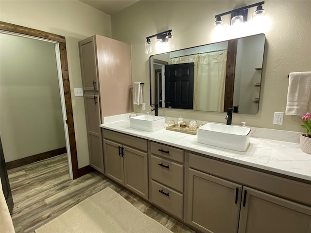 full bathroom with double vanity, wood finished floors, a shower with curtain, and a sink