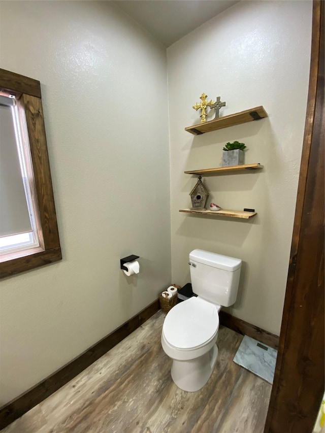 half bath featuring baseboards, wood finished floors, and toilet