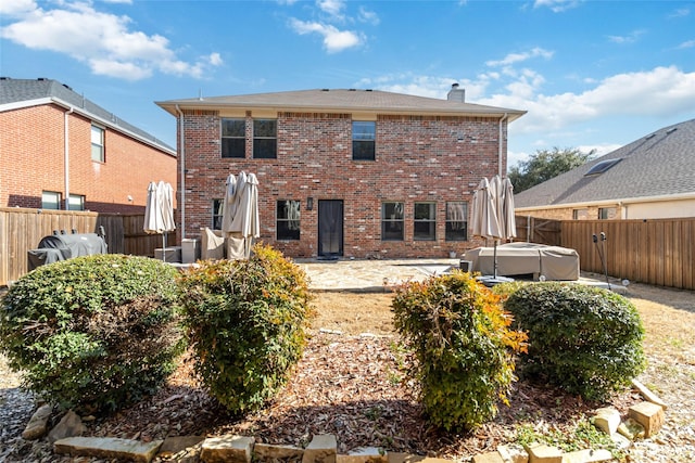 2409 Eisenhower Dr, Mckinney, TX 75071 - rear view of property featuring a patio, a fenced backyard, a chimney, brick siding, and a jacuzzi