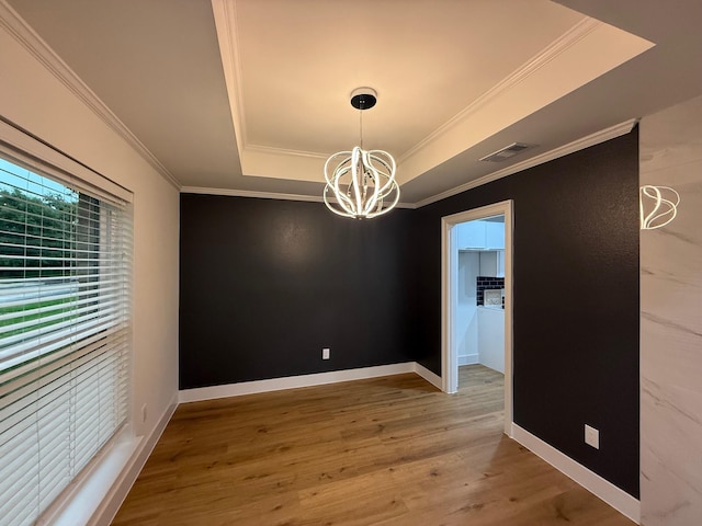 unfurnished dining area with visible vents, crown molding, wood finished floors, a raised ceiling, and an inviting chandelier