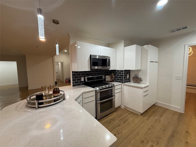 kitchen featuring appliances with stainless steel finishes, a peninsula, white cabinetry, visible vents, and pendant lighting