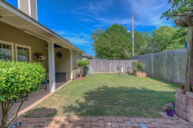 view of yard featuring a fenced backyard, central AC, and a patio