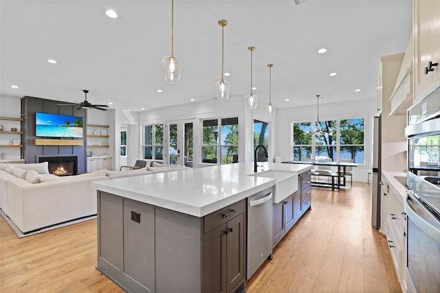 8919 Southern Shore Ct, Kemp, TX 75143 - kitchen with recessed lighting, stainless steel appliances, a sink, a fireplace, and light wood-style flooring