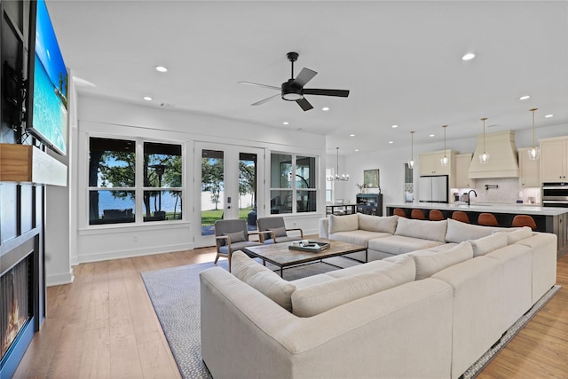 8919 Southern Shore Ct, Kemp, TX 75143 - living area with a lit fireplace, ceiling fan, recessed lighting, a chandelier, and light wood-type flooring