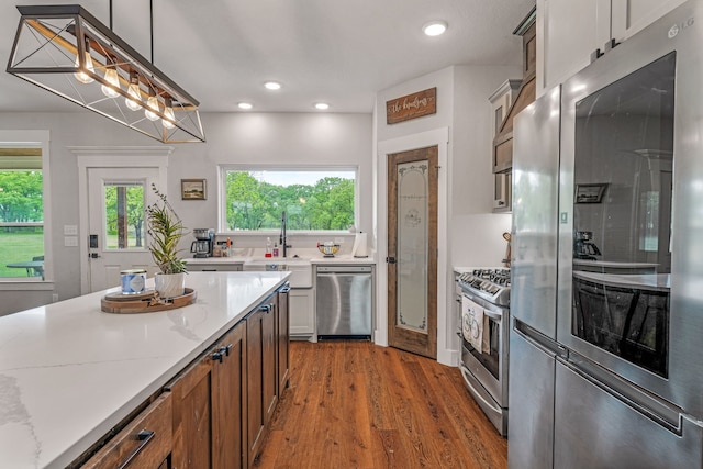 kitchen with light stone counters, wood finished floors, a sink, appliances with stainless steel finishes, and recessed lighting