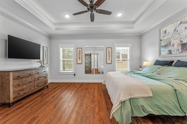 bedroom featuring wood finished floors, multiple windows, and a raised ceiling