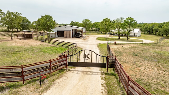 view of gate with fence, an outbuilding, and a yard