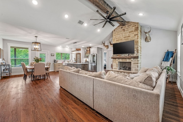 living area featuring a fireplace, visible vents, dark wood-style floors, and ceiling fan with notable chandelier