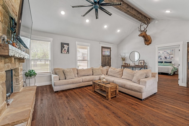 living area with a ceiling fan, a stone fireplace, wood finished floors, lofted ceiling with beams, and baseboards
