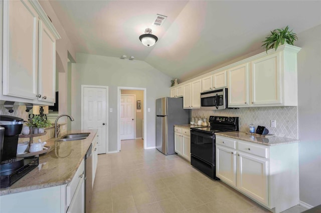 kitchen with visible vents, decorative backsplash, lofted ceiling, a sink, and appliances with stainless steel finishes