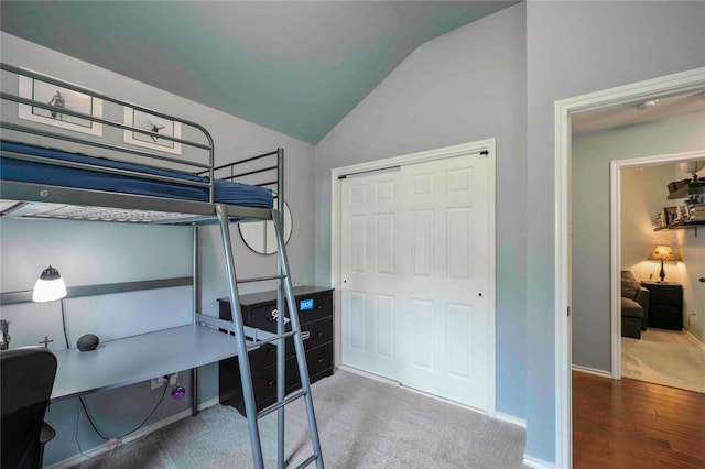 bedroom with wood finished floors, baseboards, a closet, lofted ceiling, and carpet flooring