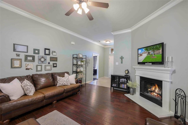 living room featuring crown molding, a glass covered fireplace, wood finished floors, baseboards, and a ceiling fan