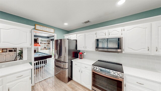 kitchen with decorative backsplash, visible vents, appliances with stainless steel finishes, light countertops, and white cabinets