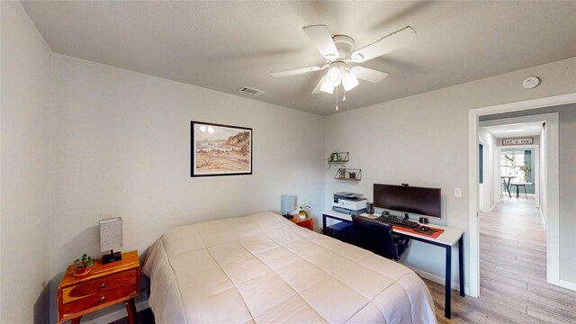 bedroom with a ceiling fan, baseboards, visible vents, and wood finished floors