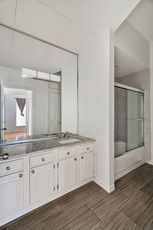 3311 Blackburn St Unit 104, Dallas, TX 75204 - full bathroom featuring baseboards, bath / shower combo with glass door, vanity, and wood finished floors