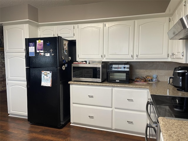 kitchen featuring wall chimney exhaust hood, freestanding refrigerator, white cabinets, and stainless steel microwave
