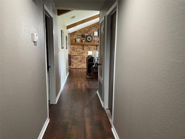 hallway featuring lofted ceiling, a textured wall, and dark wood-style flooring