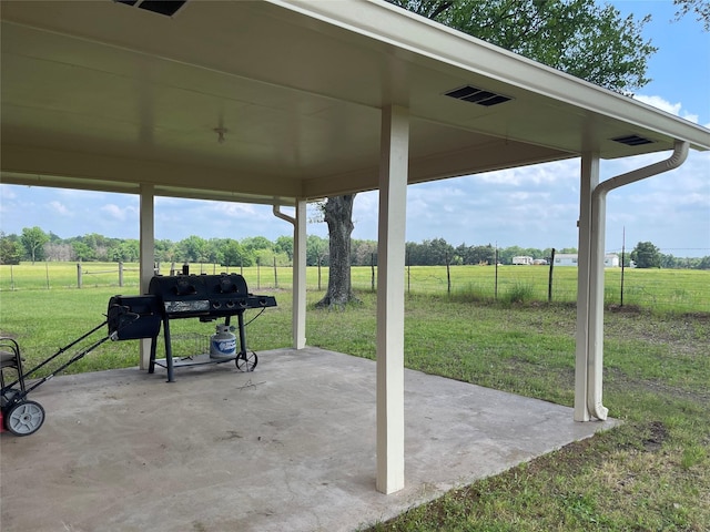 view of patio with a rural view, grilling area, a carport, and fence