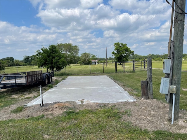 view of basketball court with fence, a lawn, and a rural view