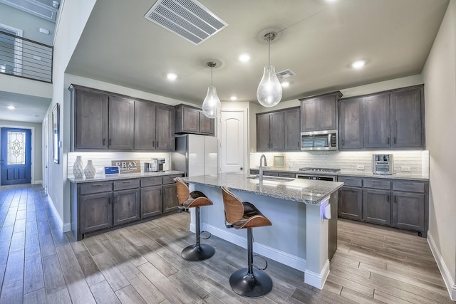 kitchen featuring visible vents, light wood-style floors, light stone counters, a sink, and stainless steel appliances