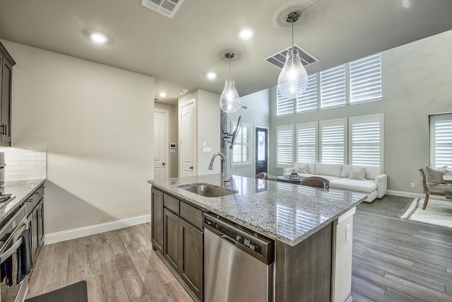 kitchen with visible vents, dark brown cabinetry, baseboards, a sink, and stainless steel appliances