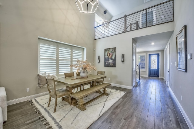dining space featuring baseboards, dark wood finished floors, and a high ceiling