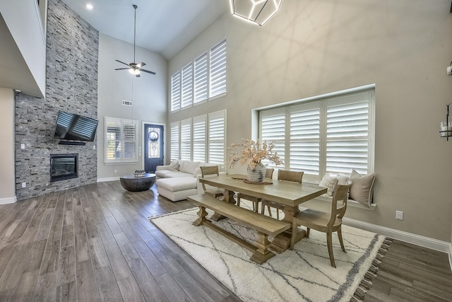 dining area with high vaulted ceiling, ceiling fan, a fireplace, and wood finished floors