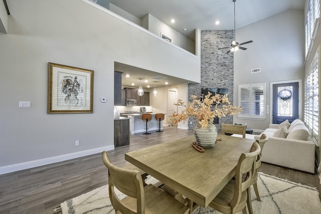 dining area with a high ceiling, dark wood finished floors, ceiling fan, and visible vents