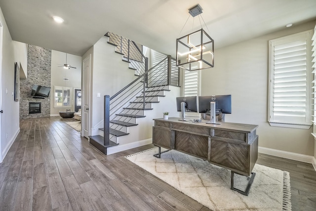 office area featuring baseboards, ceiling fan with notable chandelier, and wood finished floors