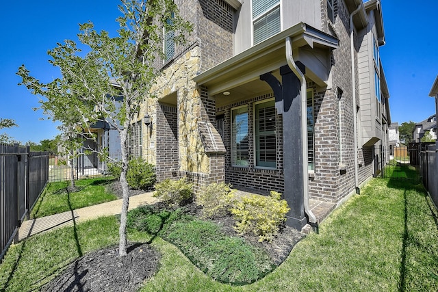 view of side of home with brick siding, a yard, and fence private yard