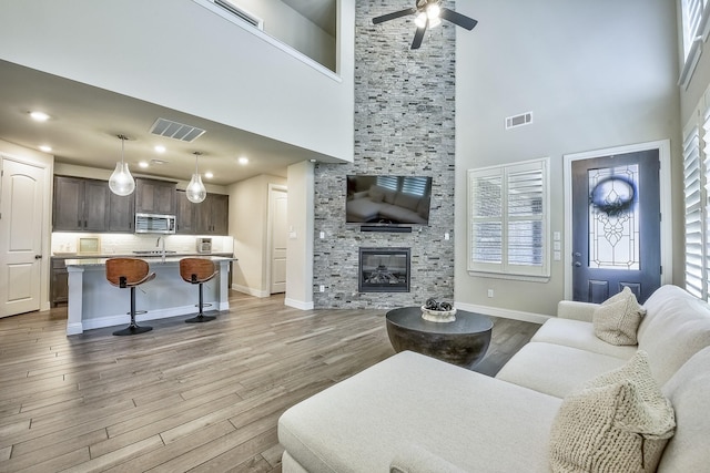 living area with visible vents, wood finished floors, and a towering ceiling