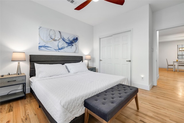bedroom with light wood-style flooring, visible vents, baseboards, a ceiling fan, and a closet