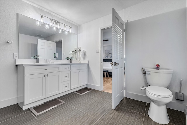 bathroom with connected bathroom, double vanity, baseboards, toilet, and tile patterned flooring