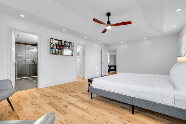 bedroom featuring a tray ceiling, baseboards, recessed lighting, wood finished floors, and ensuite bath