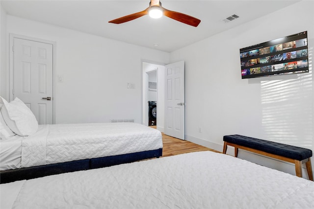 bedroom with wood finished floors, visible vents, a ceiling fan, and baseboards
