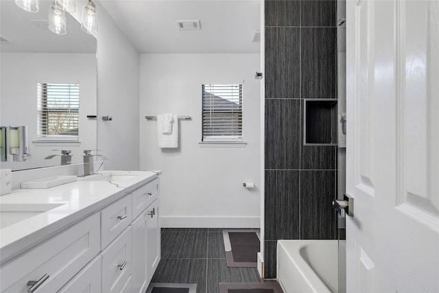 bathroom with tile patterned floors, a sink, double vanity, baseboards, and visible vents