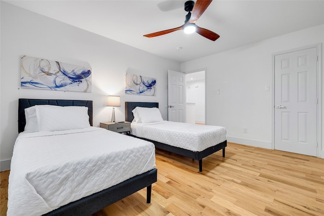 bedroom with ceiling fan, baseboards, and light wood-style flooring