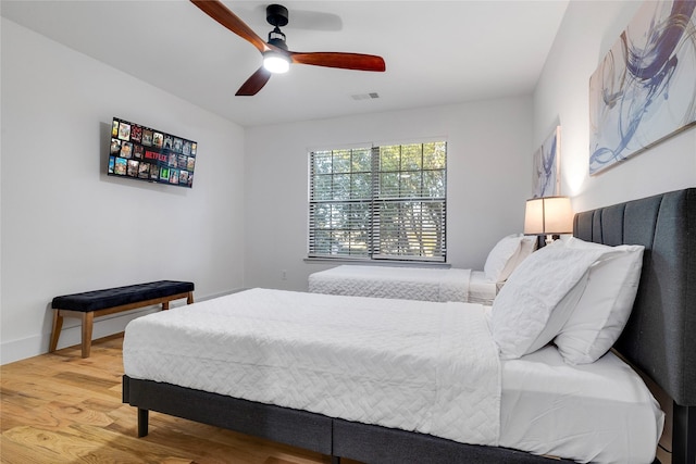 bedroom featuring visible vents, baseboards, wood finished floors, and ceiling fan